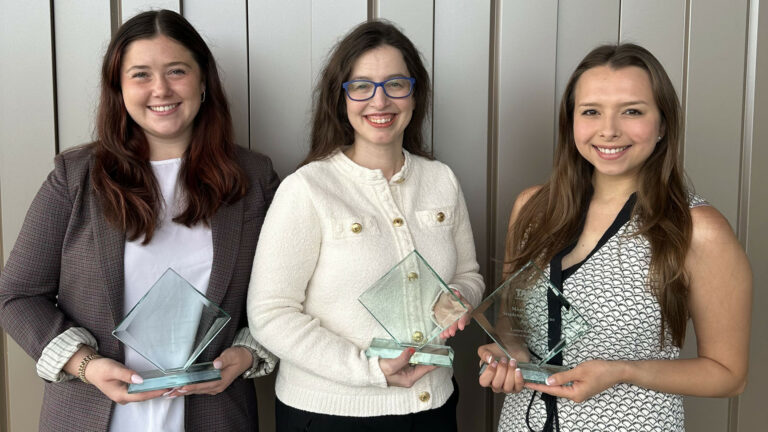 Dr. Sofia Georgiadou (middle), Sophi Synek, and Lauren Godfrey all won an award at the annual TAMFT Conference and are holding their awards and smiling into the camera.